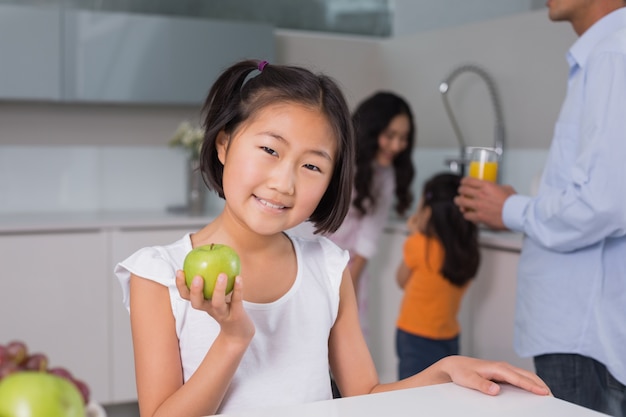 Souriante jeune fille avec la famille en arrière-plan dans la cuisine