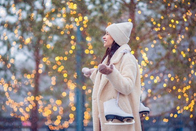 Souriante jeune fille patinant sur la patinoire à l'extérieur