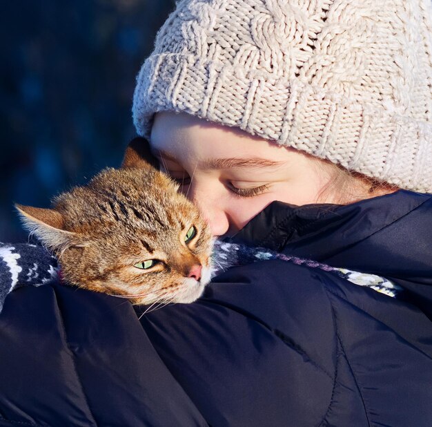 Souriante jeune fille tenant son chat à l'extérieur