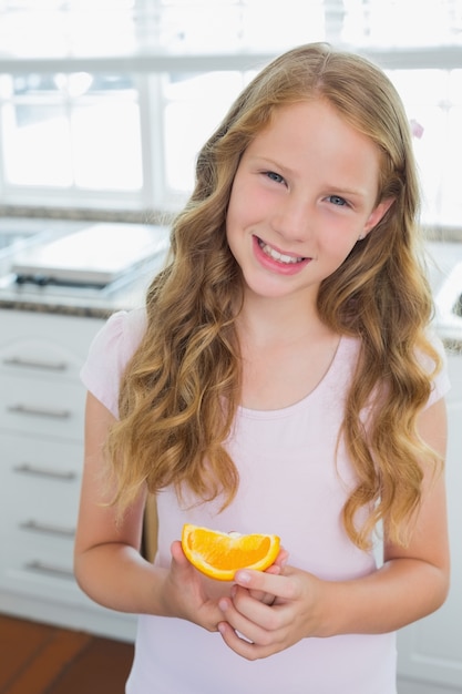 Souriante jeune fille avec une tranche de sweetlime dans la cuisine