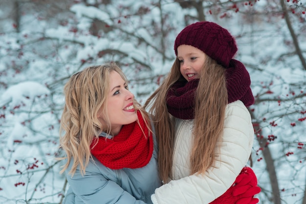 Souriante jeune mère et sa jolie fille patinage sur glace ensemble à la main.