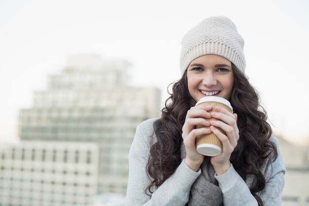 Souriante jolie brune ayant un café