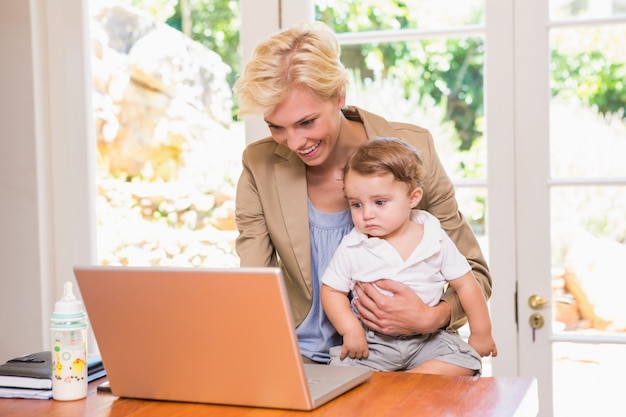 Souriante jolie femme blonde en utilisant un ordinateur portable avec son fils