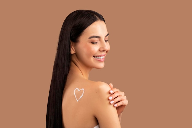 Souriante jolie femme torse nu avec symbole en forme de coeur sur l'épaule