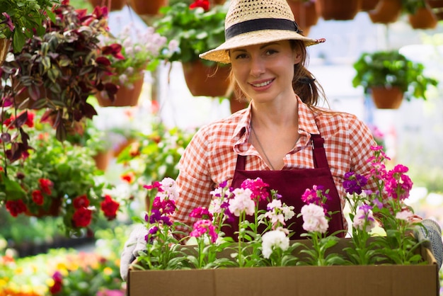 Souriante jolie jeune femme fleuriste arrangeant des plantes dans un magasin de fleurs le passe-temps est devenu un petit