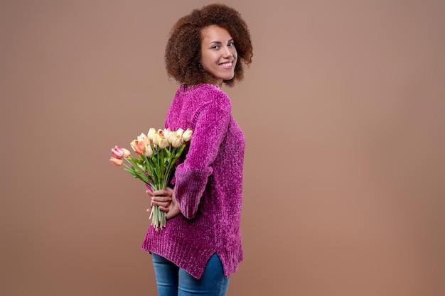 Souriante jolie jeune femme tenant un bouquet de fleurs