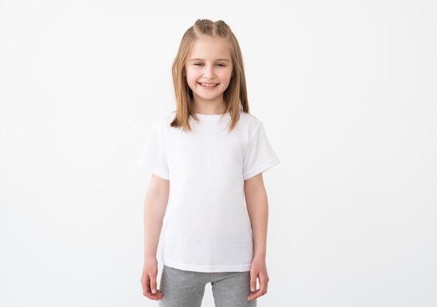 Souriante petite fille posant en t-shirt blanc vierge