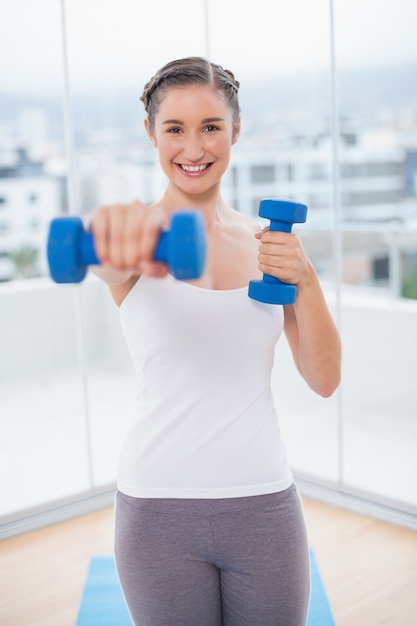 Souriante sportive brune avec des haltères