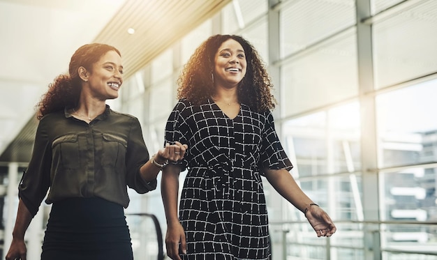 Souriez vers le haut Photo recadrée de deux jeunes femmes d'affaires séduisantes marchant dans un lieu de travail moderne