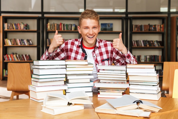 Sourire adolescent assis à la table de la bibliothèque