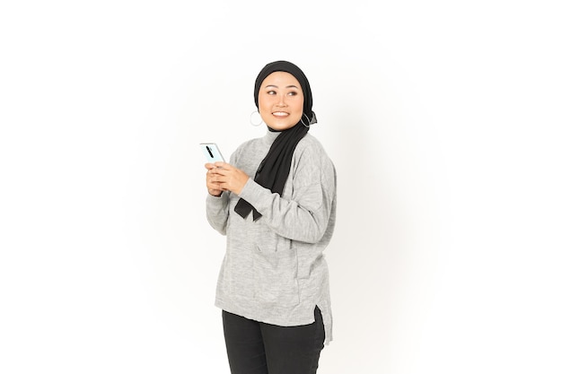 Sourire et à l'aide de Smartphone de belle femme asiatique portant le hijab isolé sur fond blanc