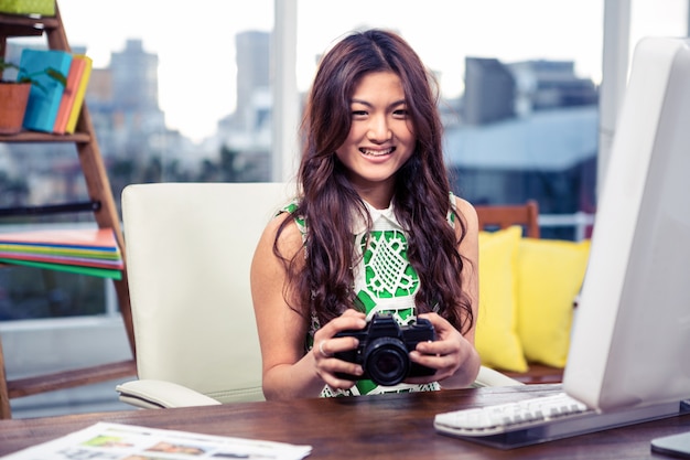 Sourire asiatique femme tenant la caméra au bureau