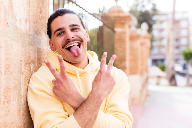 Sourire et avoir l'air heureux, amical et satisfait, gestant la victoire ou la paix avec les deux mains