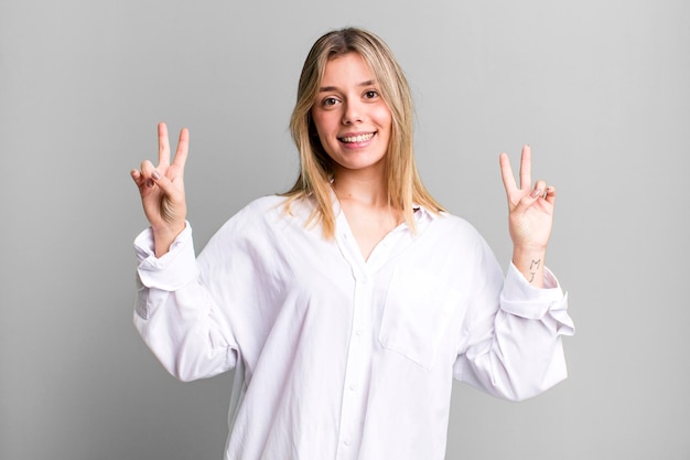 Sourire et avoir l'air heureux, amical et satisfait, gestant la victoire ou la paix avec les deux mains