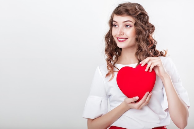 Sourire belle femme bouclée avec des ballons à air en forme de coeur pour la Saint-Valentin