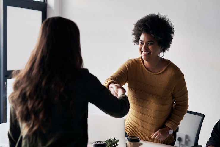 Photo le sourire des bureaux et des hommes d'affaires avec une poignée de main et un accord de collaboration dans l'agence de conception travail d'équipe créatif et femmes se serrant la main pour le succès du projet onboarding ou introduction b2b