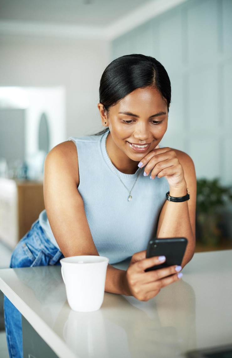 Photo le sourire café et la femme sur le téléphone portable dans la cuisine réseautage sur le site internet ou l'application mobile technologie heureux et la personne féminine tapant un courriel en ligne avec le téléphone par comptoir dans l'appartement le matin