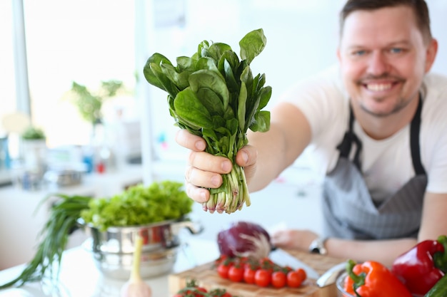 Sourire de chef montrant un paquet de fines herbes aromatiques vertes