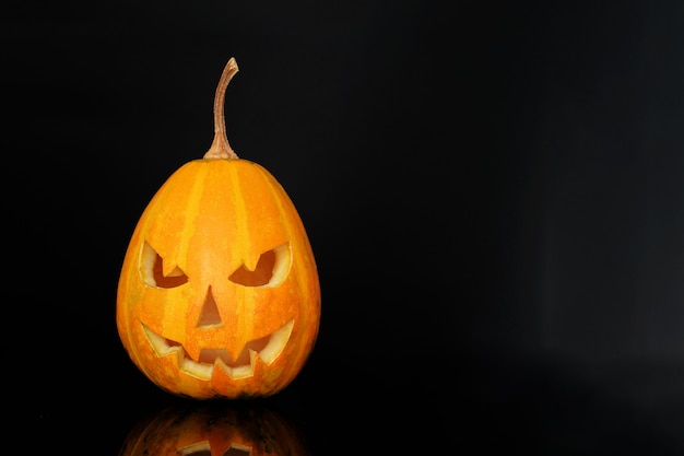 Sourire de citrouille d'Halloween et yeux effrayants pour la soirée. Vue rapprochée de la citrouille d'Halloween effrayante à fond noir.