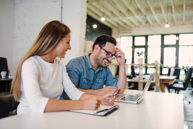 Sourire des collègues de travail travaillant dans un bureau moderne à espace ouvert.