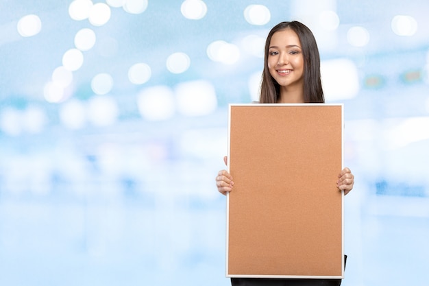 Sourire décontractée femme tenant le tableau de liège vide