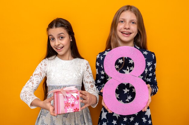 Sourire de deux petites filles le jour de la femme heureuse tenant le numéro huit avec présent