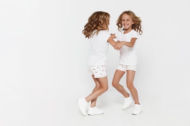 Sourire Drôle De Petites Soeurs Jumelles En Vêtements Blancs Dansant