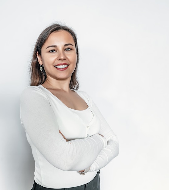 Sourire éclatant sur le visage Femme d'affaires confiante en pull blanc Elle garde les bras croisés sous la poitrine