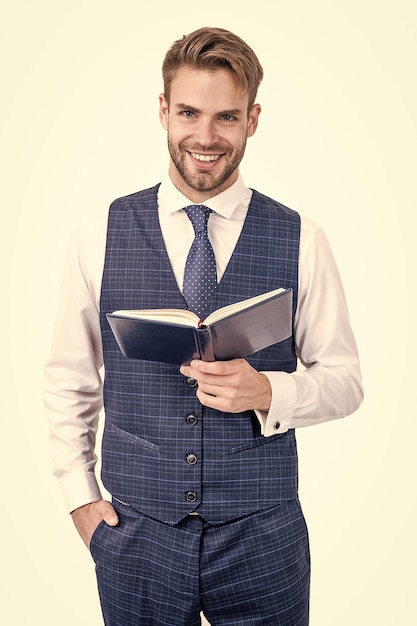 Sourire d'écolier heureux tenant un livre ouvert dans un style de mode formel isolé sur une école blanche