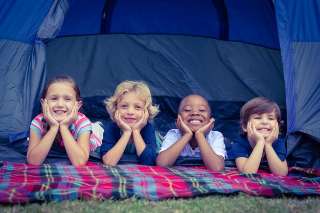 Sourire d&#39;enfants couchés dans la tente ensemble