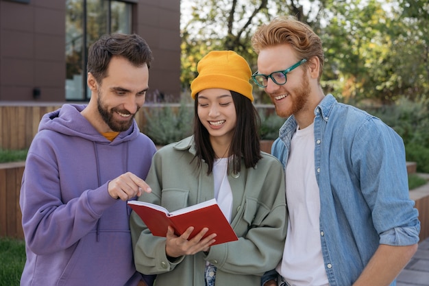 Sourire étudiant multiracial étudie ensemble la lecture de livre d'apprentissage de la langue