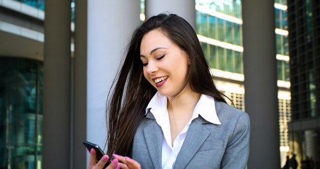 Sourire de femme d&#39;affaires à l&#39;aide d&#39;un smartphone en plein air