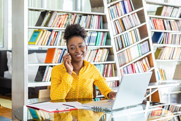 Sourire, femme affaires, conversation téléphone mobile, quoique, regarder, a, ordinateur