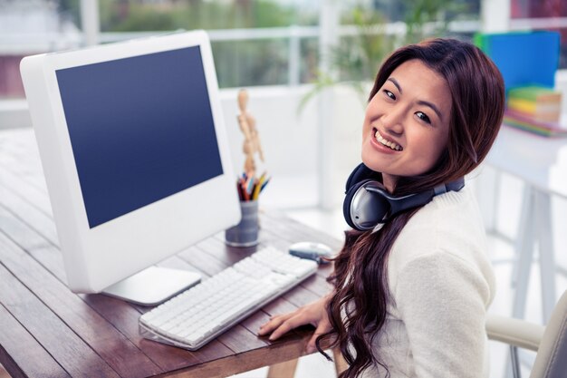 Sourire de femme asiatique avec un casque autour du cou au bureau