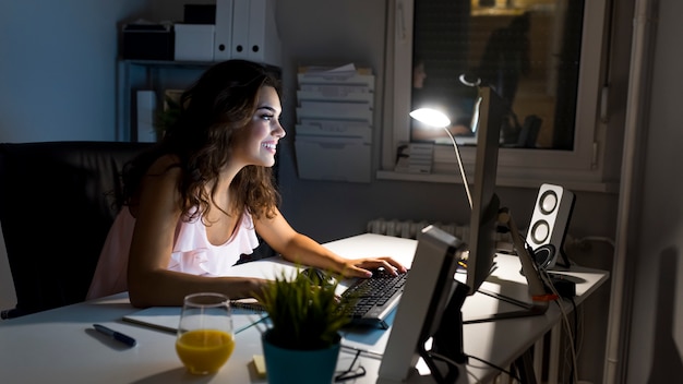 Sourire femme entrepreneur travaillant de la maison tard dans la nuit