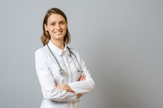 Sourire de femme médecin en blouse de laboratoire avec les bras croisés