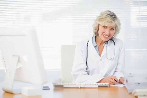 Sourire femme médecin avec ordinateur au cabinet médical