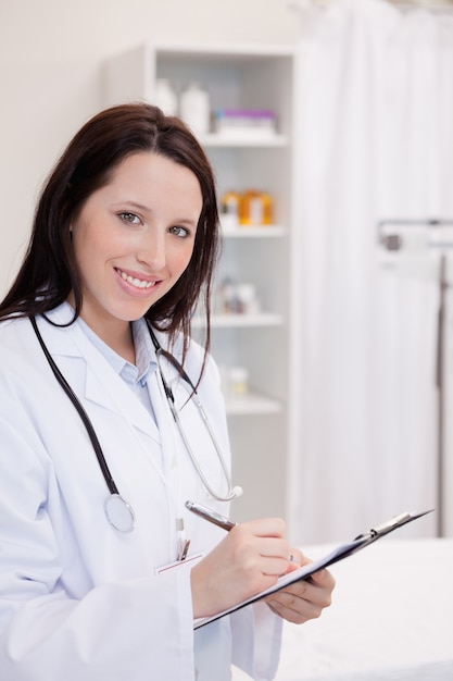 Sourire, femme médecin, prendre des notes