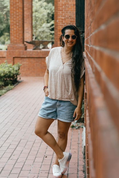 Sourire de femme se sentant bien, fond de bâtiment en brique.