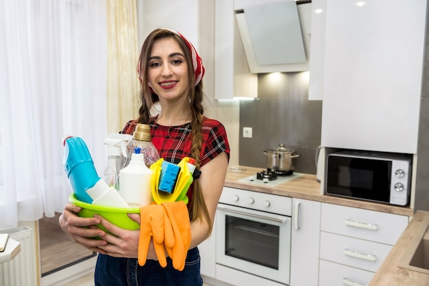 Sourire fille adulte nettoyage cuisine avec vaporisateur et un chiffon en microfibre