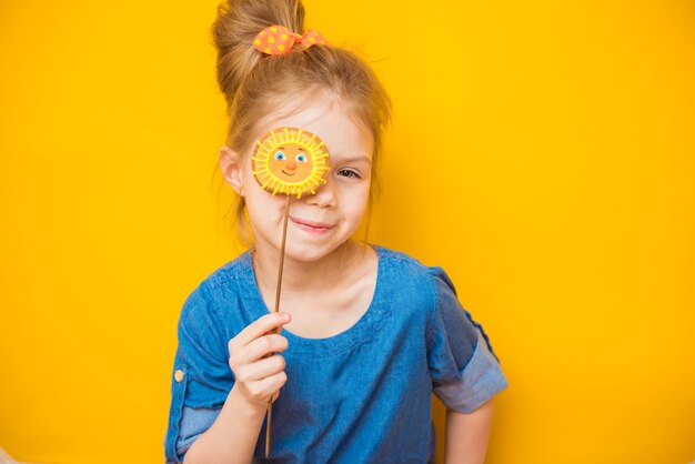 Sourire fille enfant ferme ses yeux avec du pain d'épice sur fond jaune