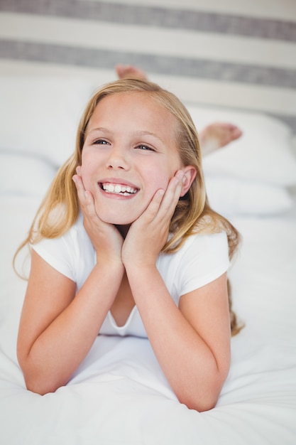 Sourire fille se détendre sur le lit