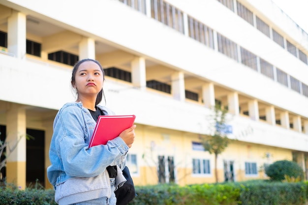 Sourire fille tenir livre rose debout sur fond de bâtiment, retour à l'école.