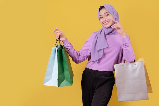 Sourire heureuse jolie fille utilisant une carte de crédit pour gaspiller de l'argent dans un centre commercial, tenant des sacs à provisions, acheter des cadeaux ou des cadeaux, offrez-vous la journée