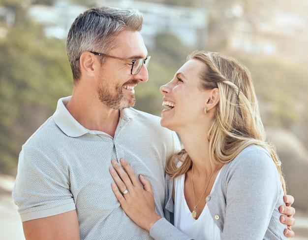 Sourire heureux et amour avec un couple à la plage pour rire, voyager et vacances d'été Bonheur vacances et romance avec un homme et une femme s'embrassant le jour de la mer pour créer des liens affectueux et attentionnés