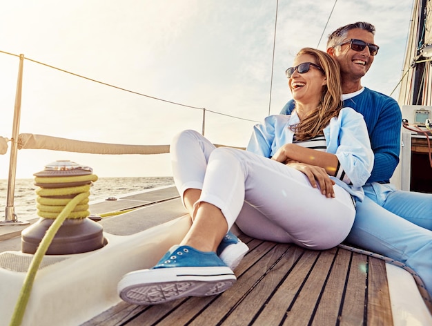 Sourire heureux et couple sur un yacht en mer Voyage d'été et aventure océanique en Espagne Câlin de paix et homme et femme sur un bateau pour une croisière de luxe voile et bonheur en vacances sur l'eau