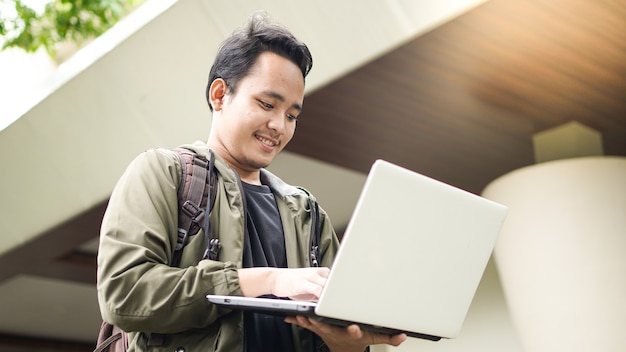 Sourire Homme Asiatique Portant Un Sac à Dos Avec Un Ordinateur Portable