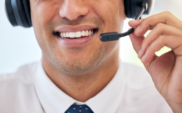 Sourire d'homme heureux et casque avec micro dans le centre d'appels pour l'assistance au service client ou le télémarketing au bureau