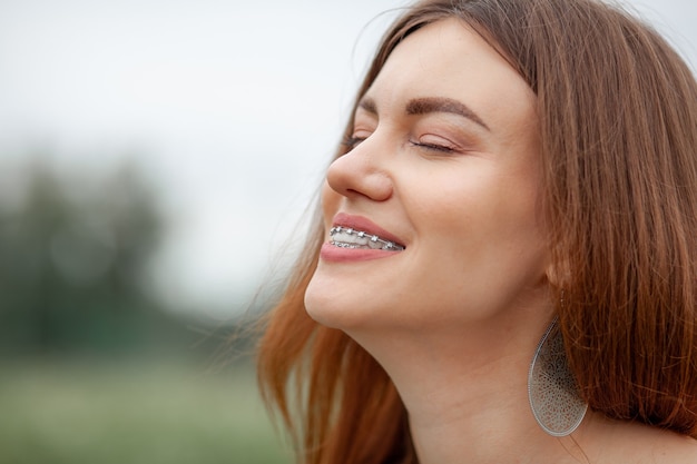 Le sourire d'une jeune et belle fille avec un appareil dentaire sur ses dents blanches. Redressement des dents tordues à l'aide d'un système de brackets. Malocclusion. Soins dentaires. Des dents lisses et un beau sourire