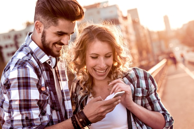 Sourire, jeune couple, regarder, téléphone portable